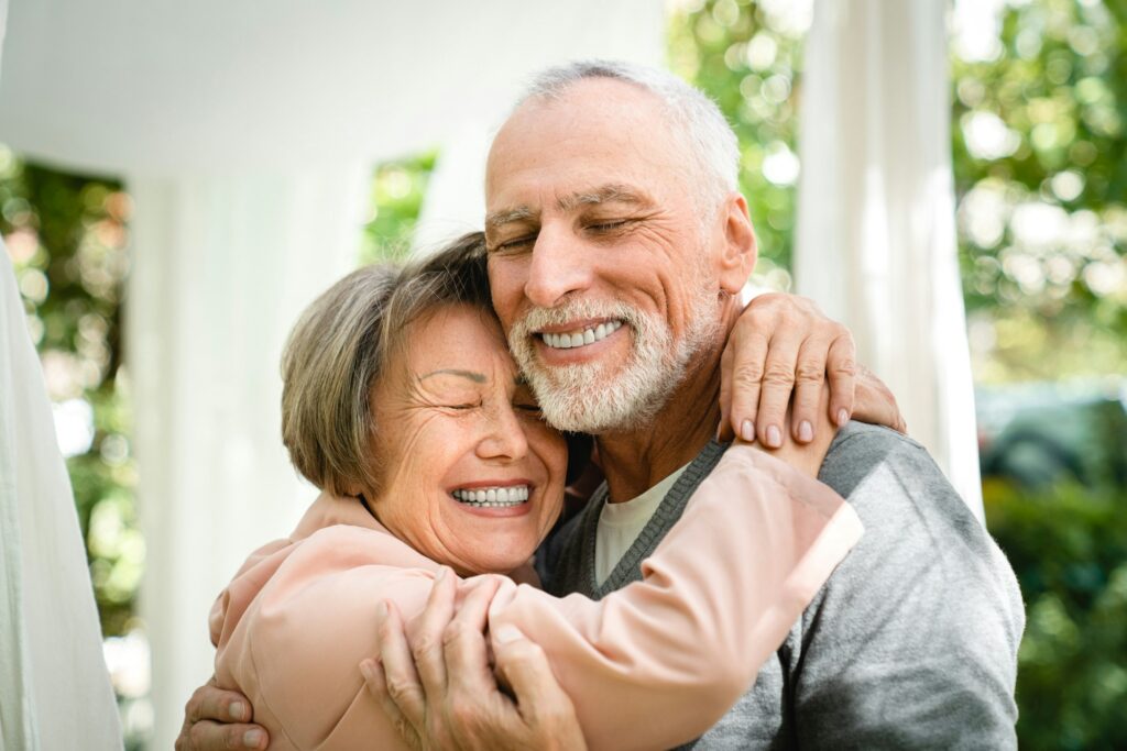 Happy senior old elderly couple spouses hugging embracing with eyes closed in garden forest