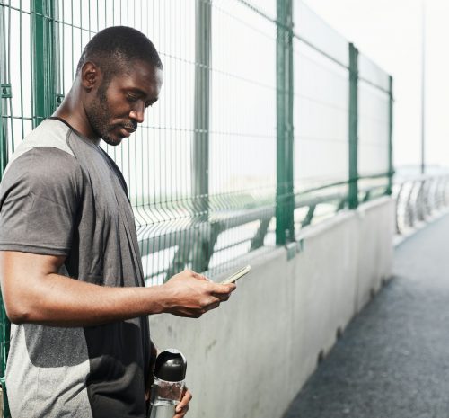 African athlete using phone outdoors