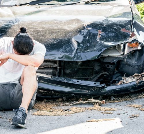Man crying on his old damaged car after crash accident